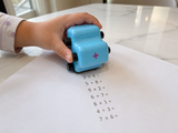 Child rolling the NumberRoll math roller stamp down a sheet of paper