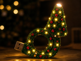 Close-up of the glowing TwinkleTree pine body with warm LEDs and red baubles